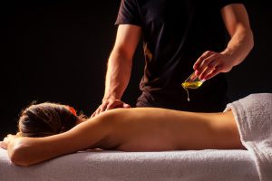 woman getting ayurvedic massage with organic oil or honeyed massagist male pouring out back